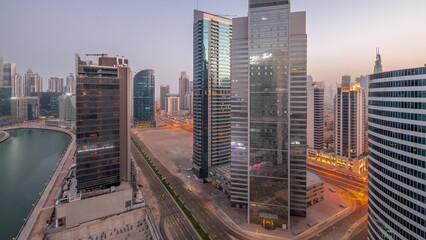 Fototapeta premium Cityscape of skyscrapers in Dubai Business Bay with water canal aerial night to day timelapse