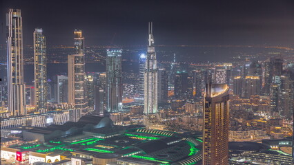 Fototapeta premium Aerial view of tallest towers in Dubai Downtown skyline and highway night timelapse.