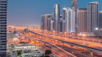 Dubai Marina skyscrapers and Sheikh Zayed road with metro railway aerial night to day timelapse, United Arab Emirates