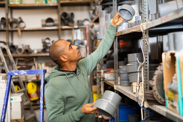 Fototapeta na wymiar Attentive man buys plumbing plastic fittings in a hardware store