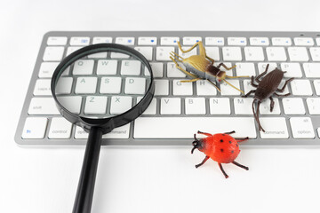 昆虫の玩具と虫眼鏡とキーボード。バグの調査イメージ