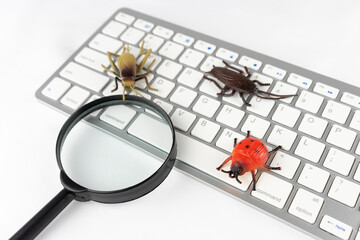 昆虫の玩具と虫眼鏡とキーボード。バグの調査イメージ