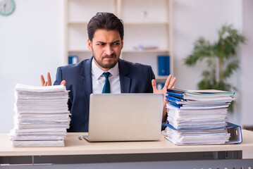 Young businessman employee and too much work in the office