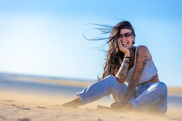 Tattooed woman laughing at the beach