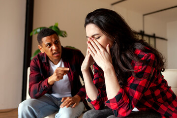 family quarrel and scandal, interracial couple quarrel at home on the couch, african american guy yells at his wife