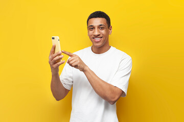 young african american man in white t-shirt uses smartphone and presses his finger on the screen on...