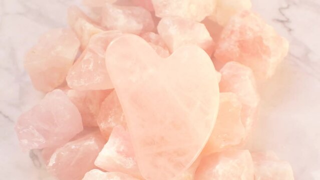 gua sha scraper.Rose quartz massage scraper in the shape of a heart from natural stone on rose quartz on gray marble background.facial massage device. 4k footage