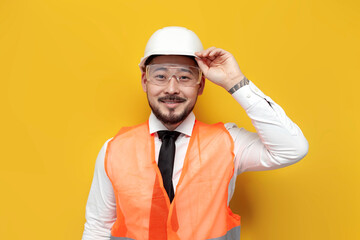 asian builder engineer in uniform on yellow isolated background, male korean man in hard hat and...