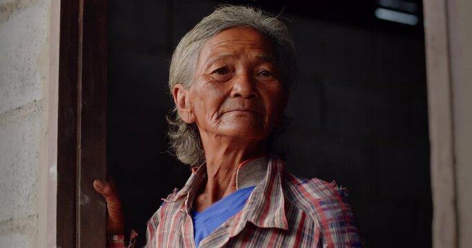Asian female farmer woman who is a poor elderly native works hard in a farm, looked up at the tourists. Used in humanity, documentary, lonely person, environment, rural area.