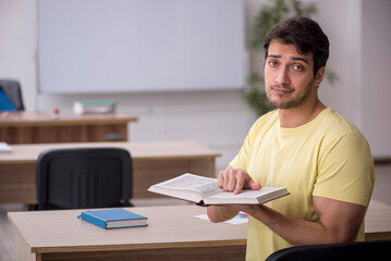 Fototapeta na wymiar Young male student teacher sitting in the classroom