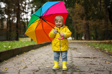 Obraz premium Little girl with colorful umbrella walking outdoors
