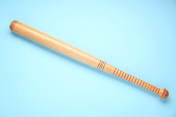 Wooden baseball bat on light blue background, top view. Sports equipment