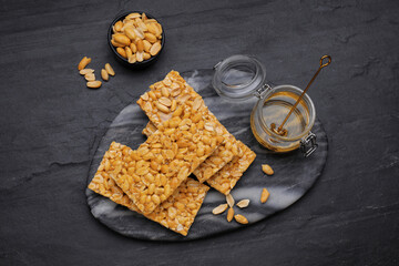 Delicious peanut bars (kozinaki) and ingredients on black table, flat lay