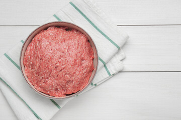 Bowl of raw fresh minced meat on white wooden table, top view. S