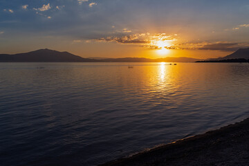 sun sets on lake chapala and mountains on horizon illuminating water in jalisco mexico