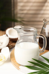 Obraz na płótnie Canvas Glass jug of delicious coconut milk on white table indoors