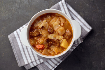 Tasty cabbage soup with meat and carrot on grey table, top view