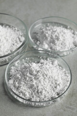Petri dishes with calcium carbonate powder on light grey table