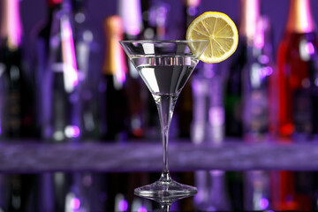Martini glass of refreshing cocktail and lemon slice on mirror surface