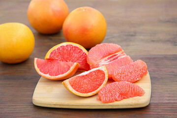 Cut and whole fresh ripe grapefruits on wooden table