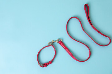 Red leather dog leash on light blue background, top view. Space for text