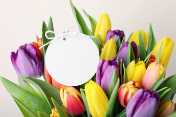 Bouquet of colorful tulips with blank card on white background, closeup