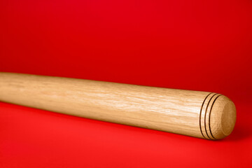 Wooden baseball bat on red background, closeup. Sports equipment