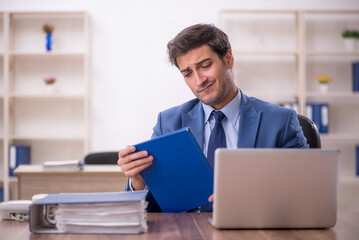 Young male employee and too much work in the office