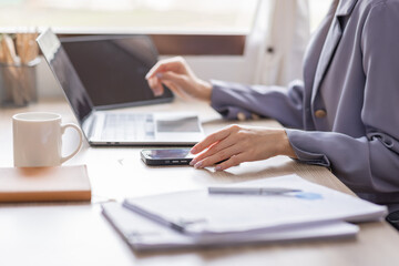 Obraz premium Happy Young Asian woman using laptop while working at home with documents. online documentation calculator to calculate the numbers, finance accounting office concept