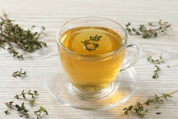 Aromatic herbal tea with thyme on white wooden table