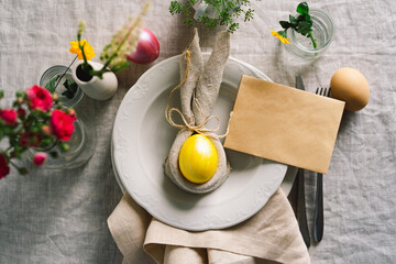 Happy Easter. Stylish easter eggs on a napkin with spring flowers on white wooden background. Table setting. The concept of a happy Easter holiday.