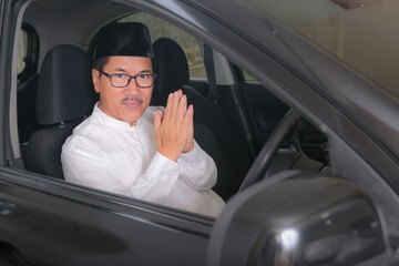 Indonesian moslem man solemnly greet from inside his car cabin.