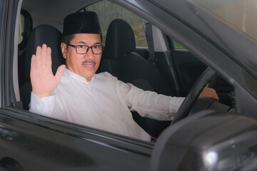 Indonesian moslem man waving his hand to say good bye from inside car cabin