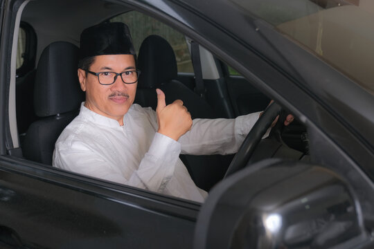 Indonesian moslem man raising his thumb up from behind steering wheel of his car