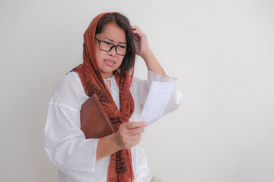 Woman scratching her head looking at shopping bill in here hand