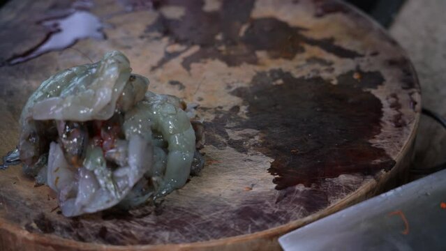 A chef in the kitchen is back-opening and delinting fresh shrimp