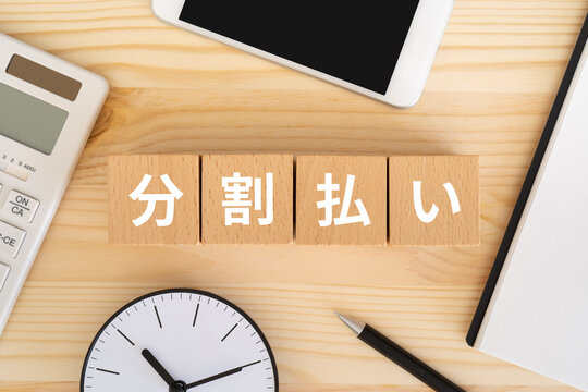 分割払いと書かれたブロック、電卓、スマホ、ノート、時計