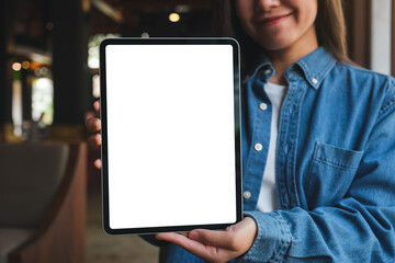 Mockup image of a woman holding and showing digital tablet with blank white desktop screen