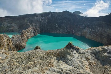 Panoramic view over the volcano Mount Kelimutu in Ende on Flores with its two sunlit turquoise...