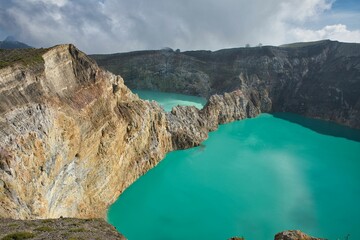 Panoramic view over the volcano Mount Kelimutu in Ende on Flores with its two sunlit turquoise...