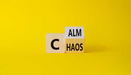 Calm vs chaos symbol. Turned wooden cubes with words Chaos and Calm. Beautiful yellow background. Business and Calm vs chaos concept. Copy space.