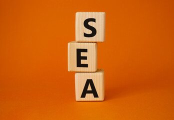 SEA - Search Engine Advertising symbol. Wooden cubes with words SEA. Beautiful orange background....