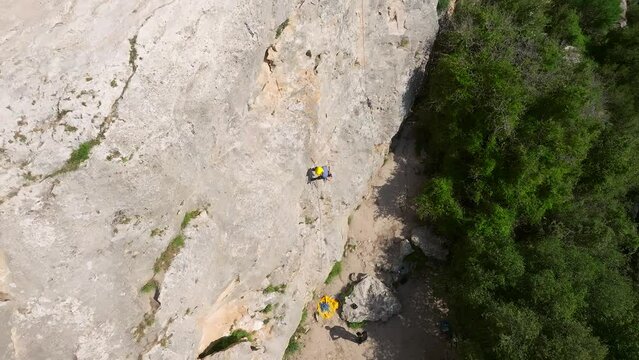 Climber rappelling down cliff with helmet and backpack