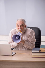 Old male teacher holding megaphone in the classroom