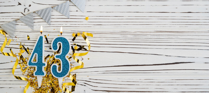 Number 43 blue celebration candle on white wooden background. Happy birthday candles. Concept of celebrating birthday, anniversary, important date, holiday. Copy space.