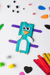 Children's funny craft made of wooden sticks and paper in the form of a bird. Children's creativity