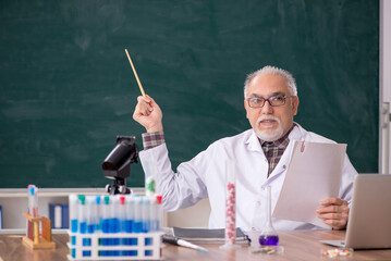 Old male teacher chemist sitting in the classroom