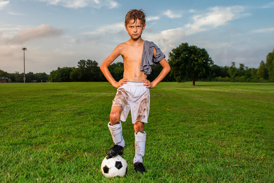 Hot and sweaty young soccer player posing with shirt off after soccer game