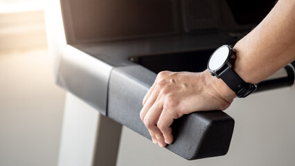 Runner man wearing smartwatch while using treadmill running in fitness gym. Wearable device for sport activity. Smart watch technology for health tracking. Healthy lifestyle concept.