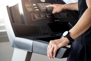 Runner man wearing smartwatch while using treadmill running in fitness gym. Wearable device for sport activity. Smart watch technology for health tracking. Healthy lifestyle concept.